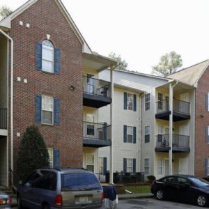 Woodland Ridge, a three-story apartment building with cream siding and brick accent walls.