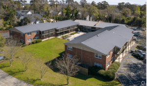 An aerial view of the Oakridge Apartments, a U-shaped building with brick siding and a pool in the middle