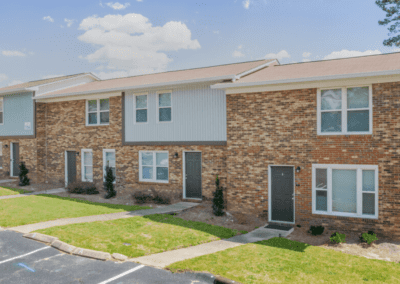 A four-unit building in the Cedar Heights townhome community. The exterior is brick with some light corrugated aluminum accent panels. The front doors are all a very dark grey