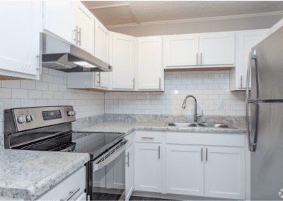 A U-shaped kitchen with white cabinets, a tile backsplash, and stainless steel appliances