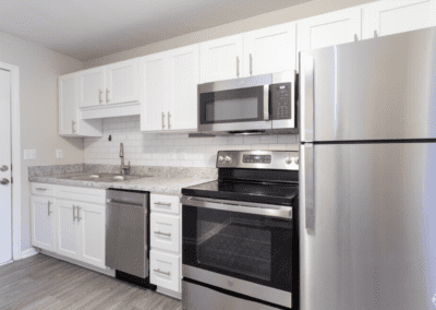 A white kitchen with tile backsplash and stainless steel appliances