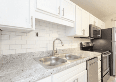 A white kitchen with tile backsplash and stainless steel appliances