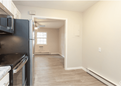 A galley kitchen with stainless steel appliances and a view of the living room through an archway