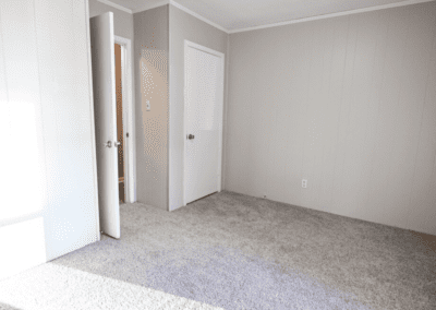 An empty bedroom with light carpet and white paneled walls