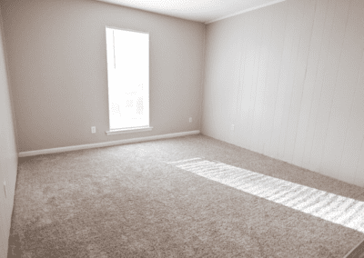 An empty bedroom with light carpet and white paneled walls