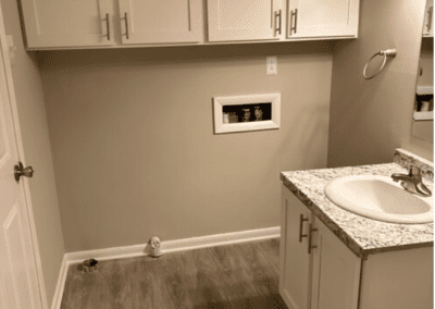 The corner of a bathroom with white cabinets on the wall and washer and dryer hookups