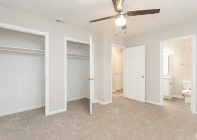 An empty bedroom with two closets and an en-suite bathroom