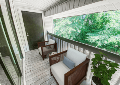 A balcony area with two outdoor chairs and a potted plant