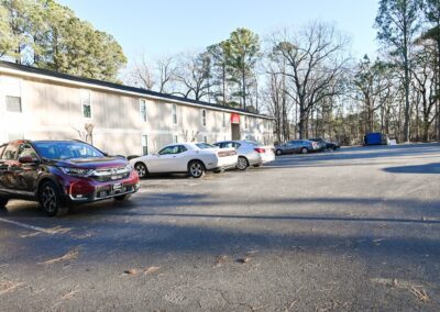 A long, beige apartment building with a large parking lot in the Magnolia Crossing apartment community