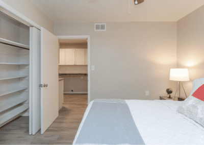 A bedroom with a queen-sized bed and a large closet. We can see the kitchen with washer and dryer hookups through the door.