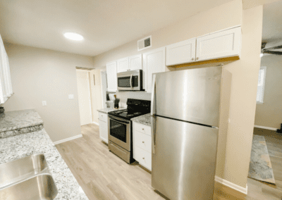 A galley style kitchen with white cabinets and stainless steel appliances